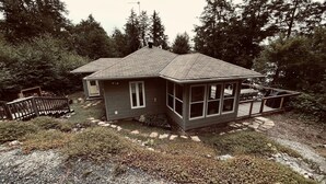Ein zweistöckiges Haus mit überdachter Veranda, einem umzäunten Deck und einer Auffahrt, die zum Eingang führt.