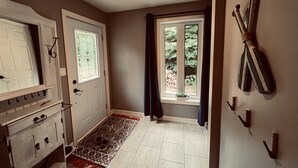 Ein Flur mit Teppichmuster, einem Holzschrank, einer Tür mit Fenster und einem Wandhaken für Kleidung.