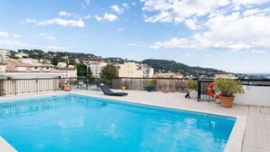 Una piscina en la azotea con vistas despejadas del paisaje urbano y las colinas al fondo.
