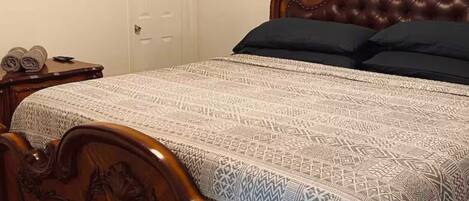 Un dormitorio con una cama de madera, un ventilador de techo, un cuadro en la pared y una puerta.