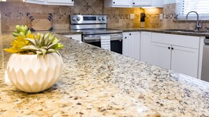 A kitchen with white cabinets, a stainless steel oven, a microwave, and a granite countertop. - Skyline Breeze - Minutes from downtown Jensen Beach (Jensen Beach)