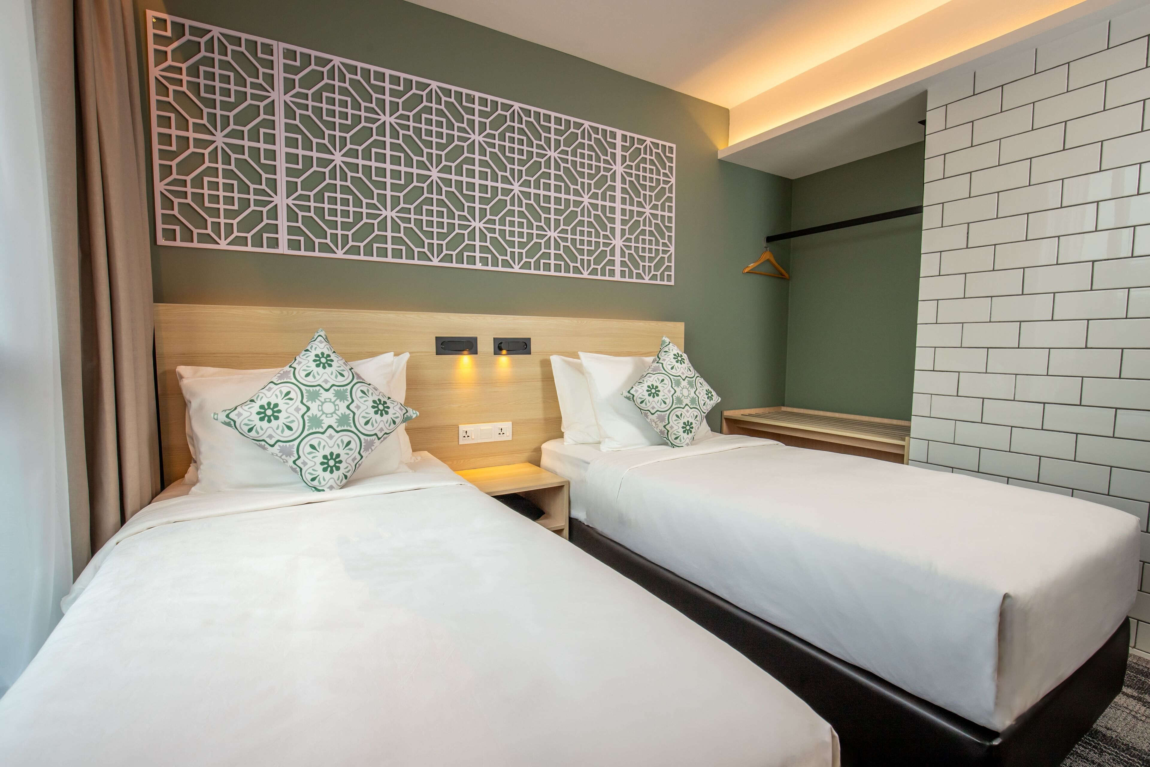 A hotel room with two beds, a decorative wall panel, a mirror, and a tiled wall.