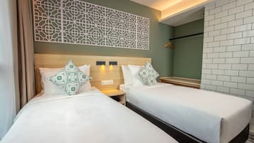 A hotel room with two beds, a decorative wall panel, a mirror, and a tiled wall.
