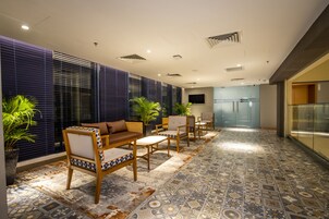 A modern lounge area with a sofa, chairs, and potted plants.