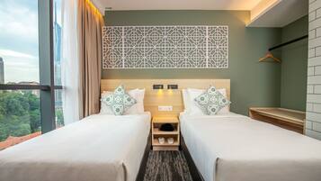 Une chambre d’hôtel avec deux lits, une décoration murale aux motifs géométriques, une vue sur la ville et une petite table de chevet en bois sur laquelle sont posées des chaussures.