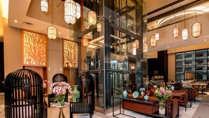 A modern lobby with glass partitions, black cushioned seating, and hanging pendant lights. - Santa Grand Signature Kuala Lumpur (Kuala Lumpur)