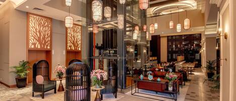 Un vestíbulo moderno con zonas de estar, un mostrador de recepción e iluminación decorativa.