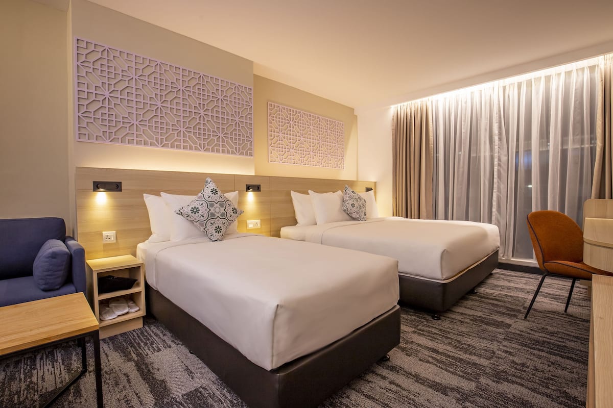 A hotel room with two beds, a sofa, a desk, and a chair.