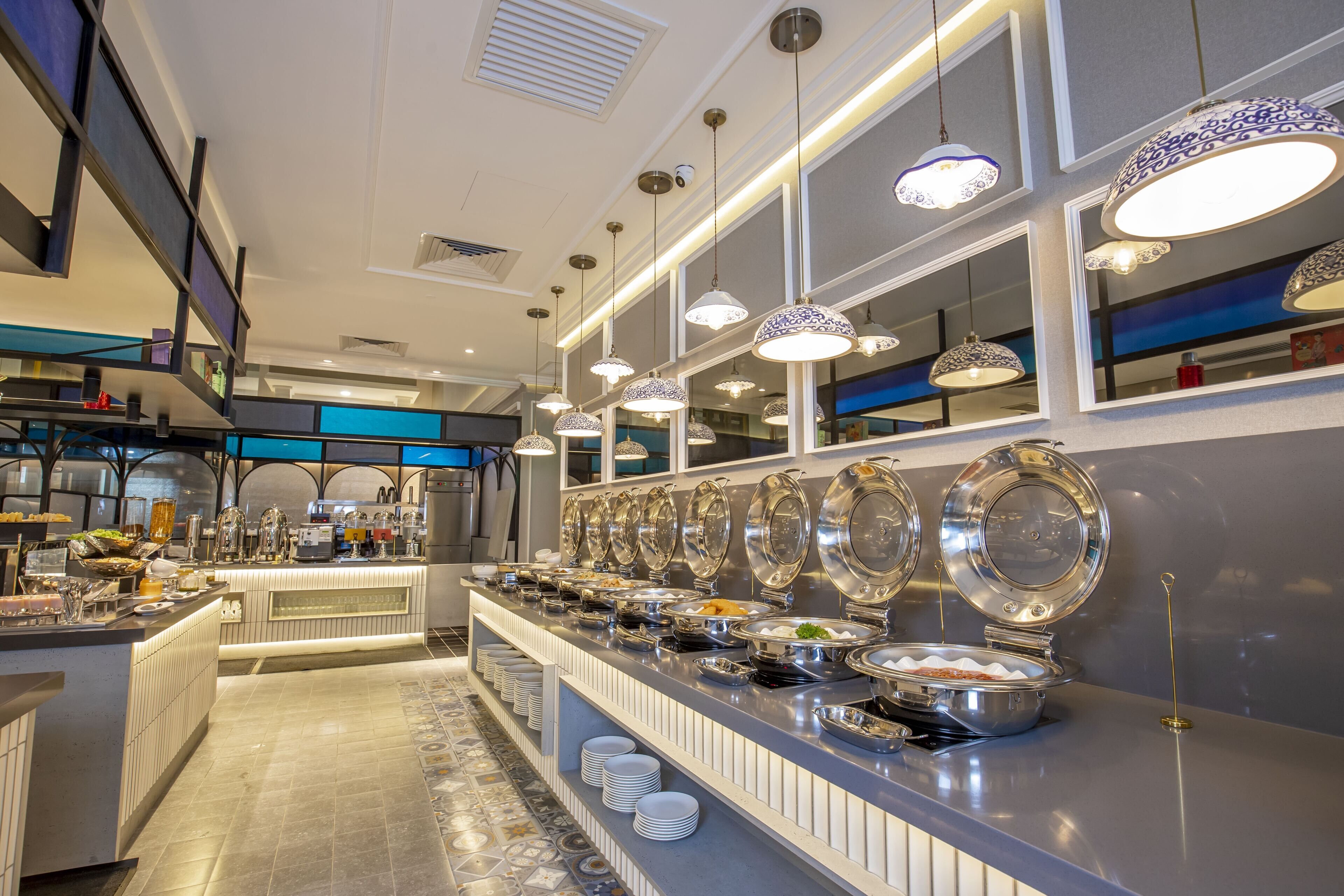 A buffet setup with multiple serving stations, a variety of food items, and overhead decorative lighting.