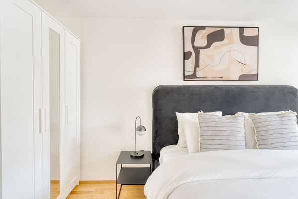 Une chambre à coucher comprenant un lit, une table de chevet, une lampe sur pied et une armoire.