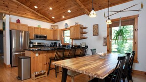 Una cocina moderna con armarios de madera, electrodomésticos de acero inoxidable y una gran mesa de comedor de madera.