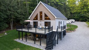 Une cabane dotée d’une terrasse, de meubles de jardin et d’un escalier menant à l’entrée principale.