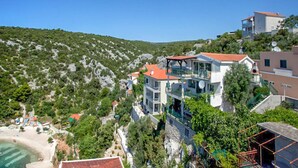 A coastal residential area with modern houses, a beach, and a mountainous backdrop.