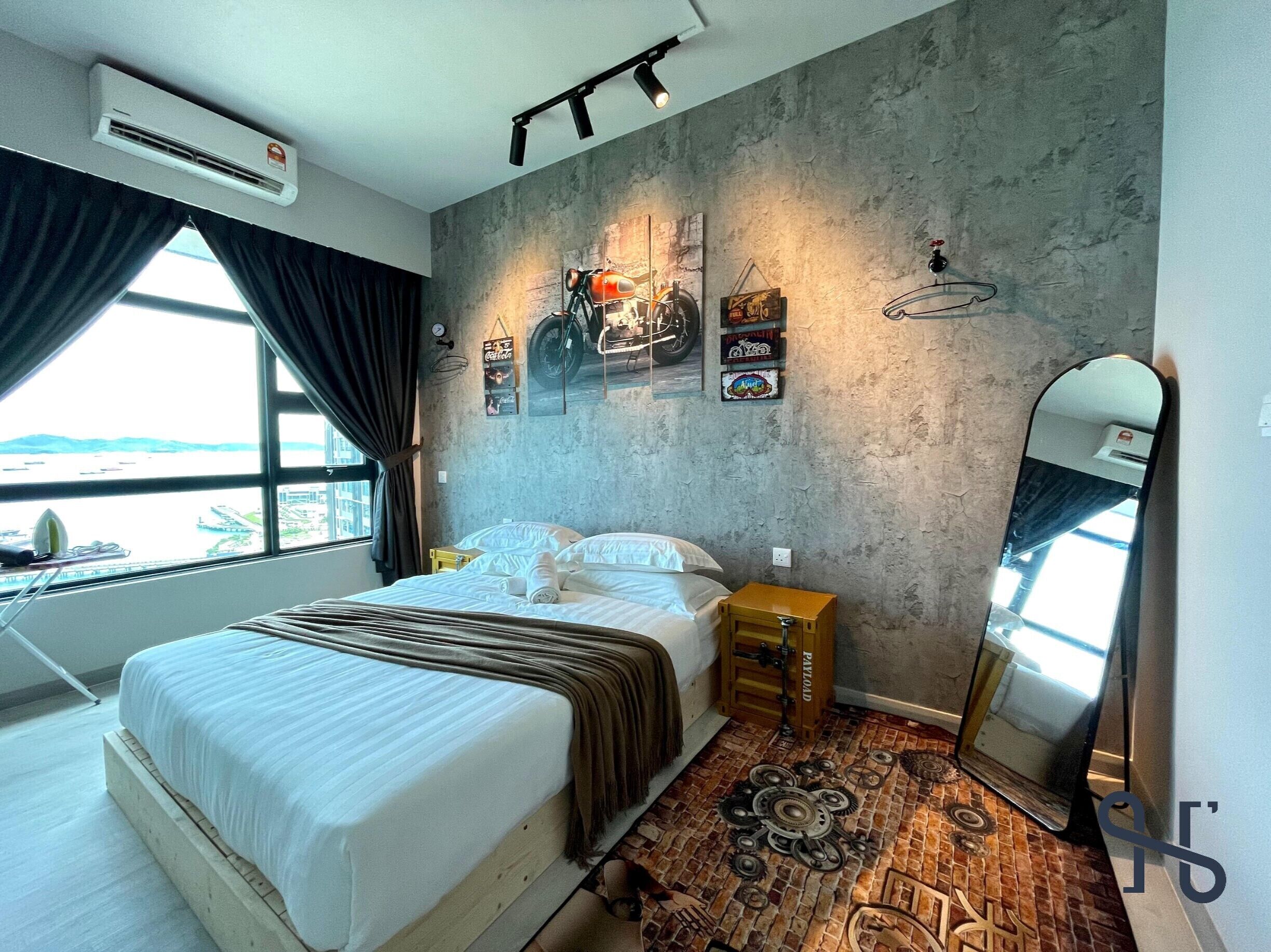 A hotel room with a bed, a small wooden nightstand, a mirror, and a window with curtains.