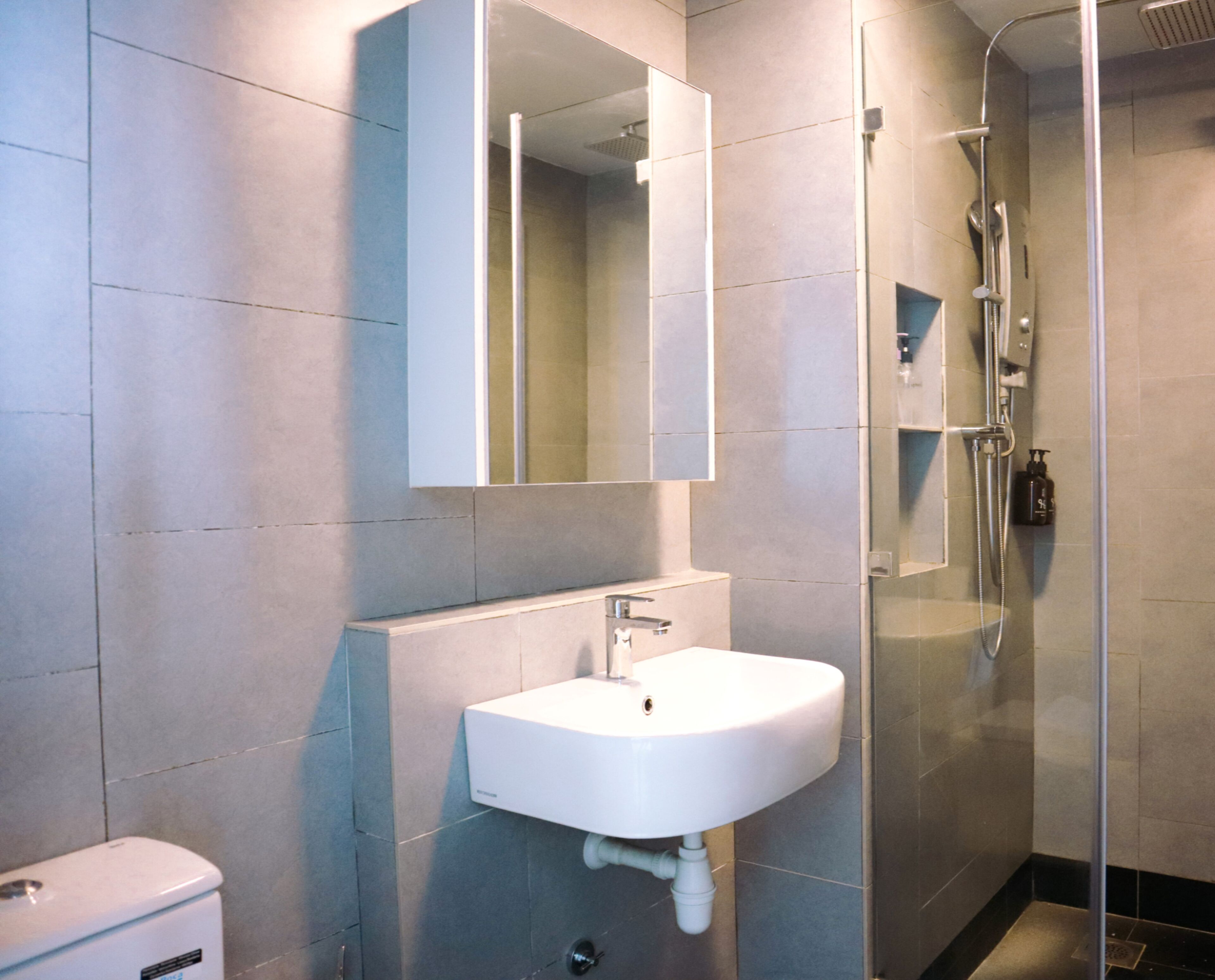 A modern bathroom with a white sink, a glass shower enclosure, and a mirror above the sink.