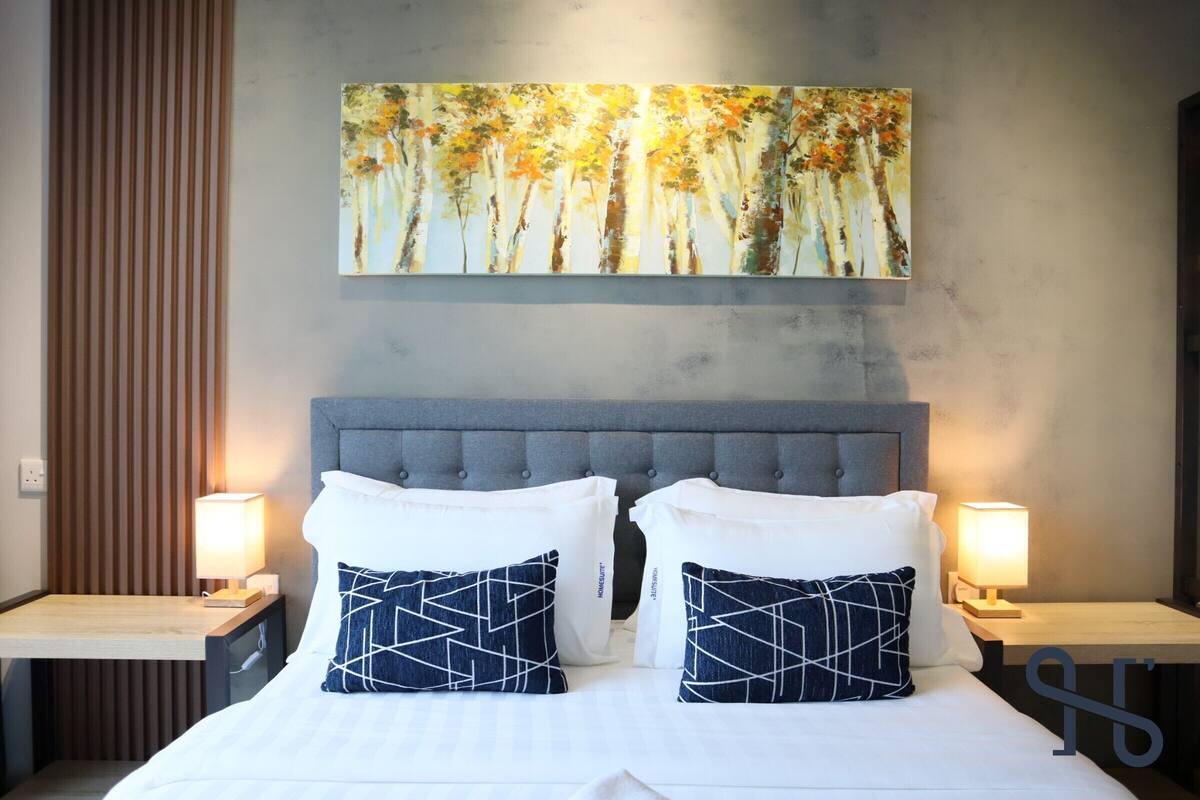 Une chambre d’hôtel avec un grand lit, deux tables de chevet avec des lampes et un tableau au-dessus du lit.