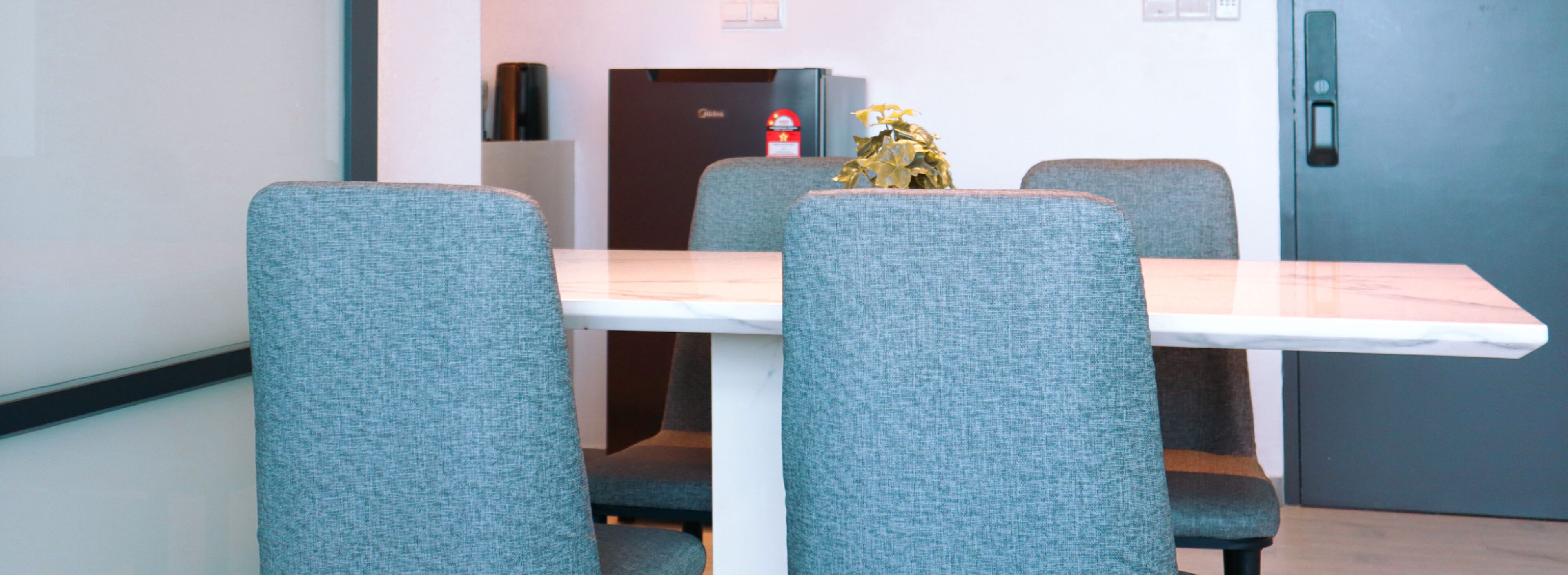 A dining area with a white table and grey upholstered chairs.