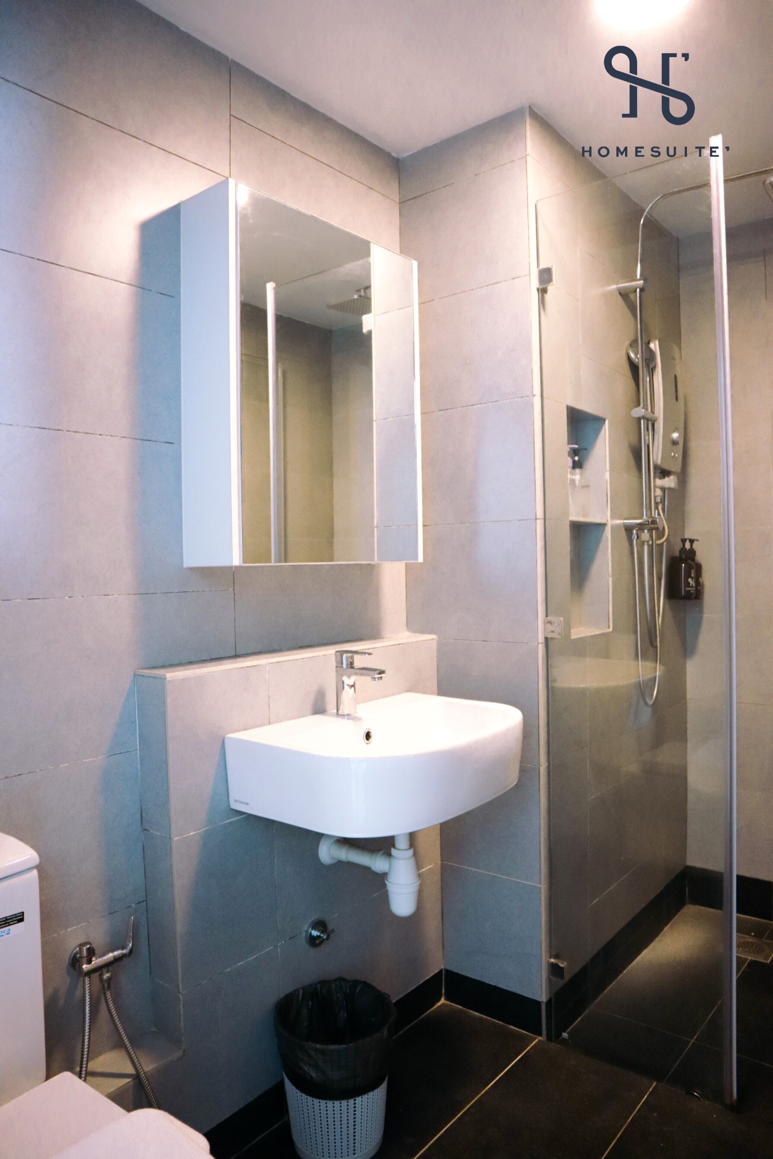 Une salle de bain moderne avec un lavabo blanc, un grand miroir et une douche à parois de verre.