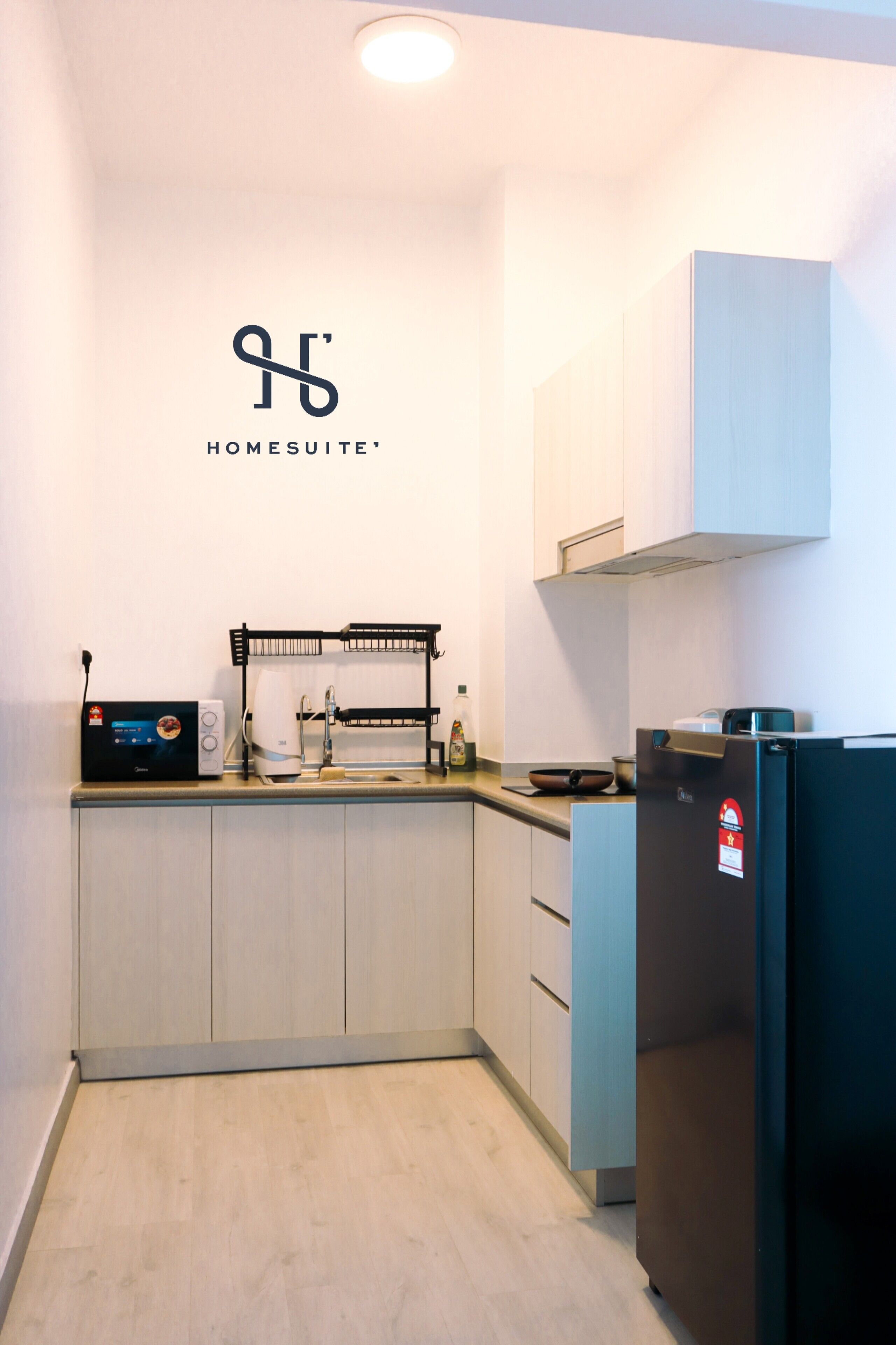 A modern kitchen with white cabinets, a black refrigerator, and a microwave.