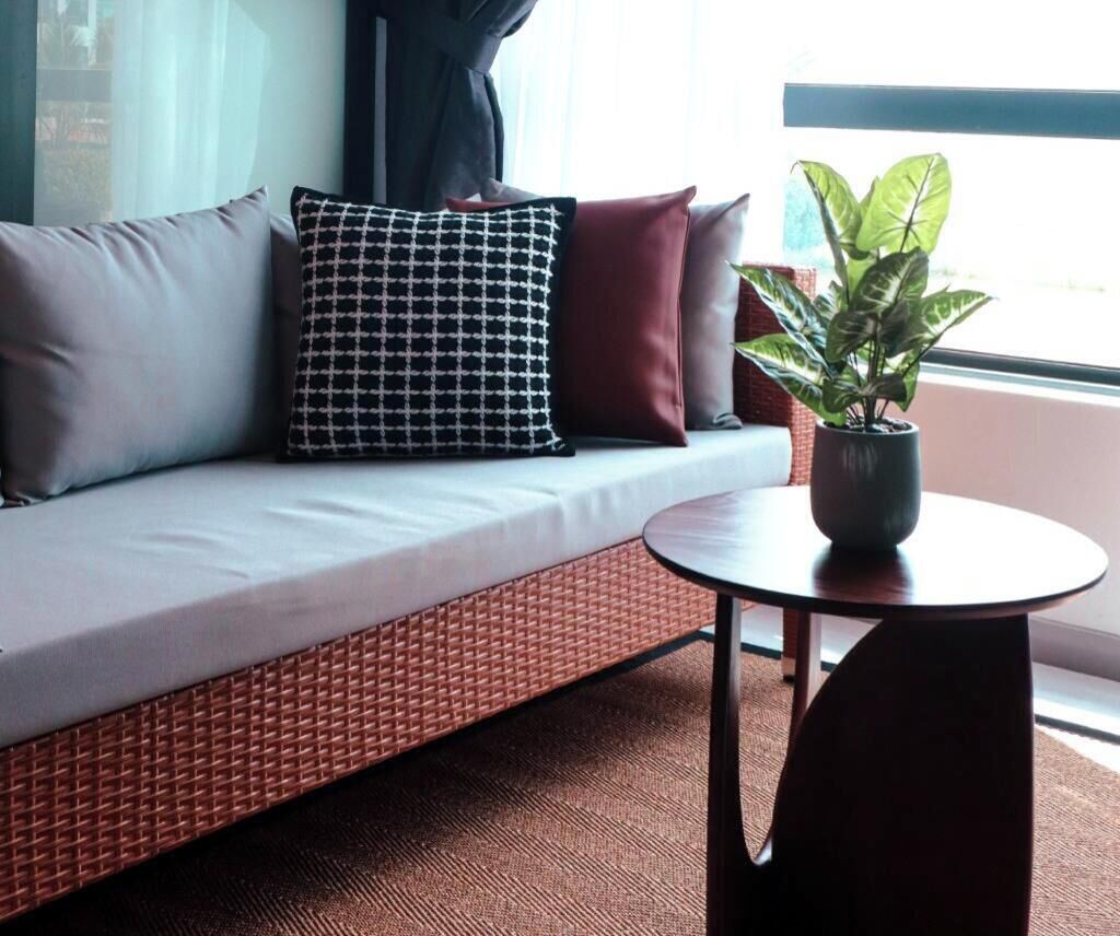 A modern hotel room with a sofa, a small table, and a potted plant.