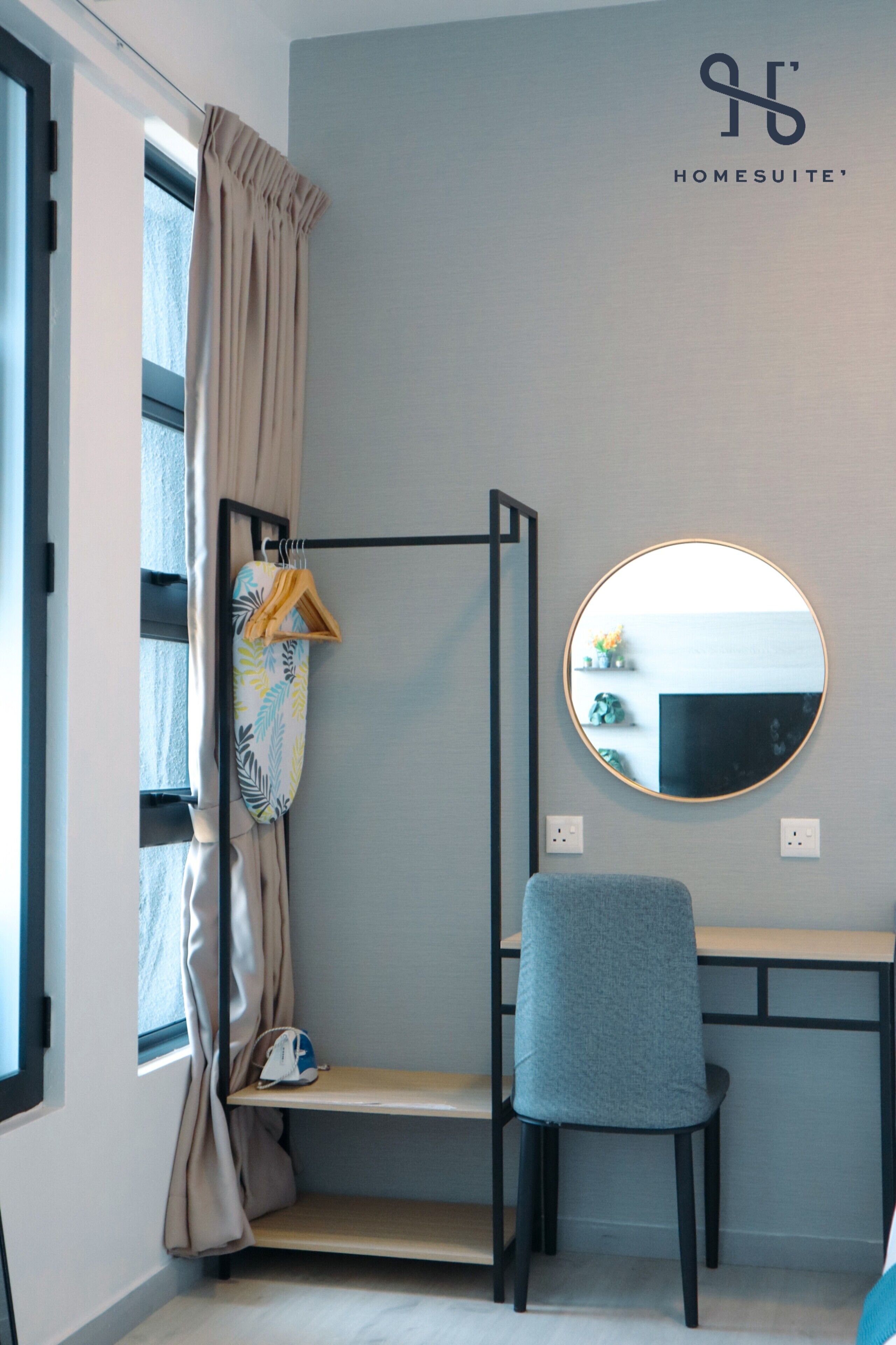 A room with a bunk bed, a desk, a chair, a round mirror, and a window with curtains.