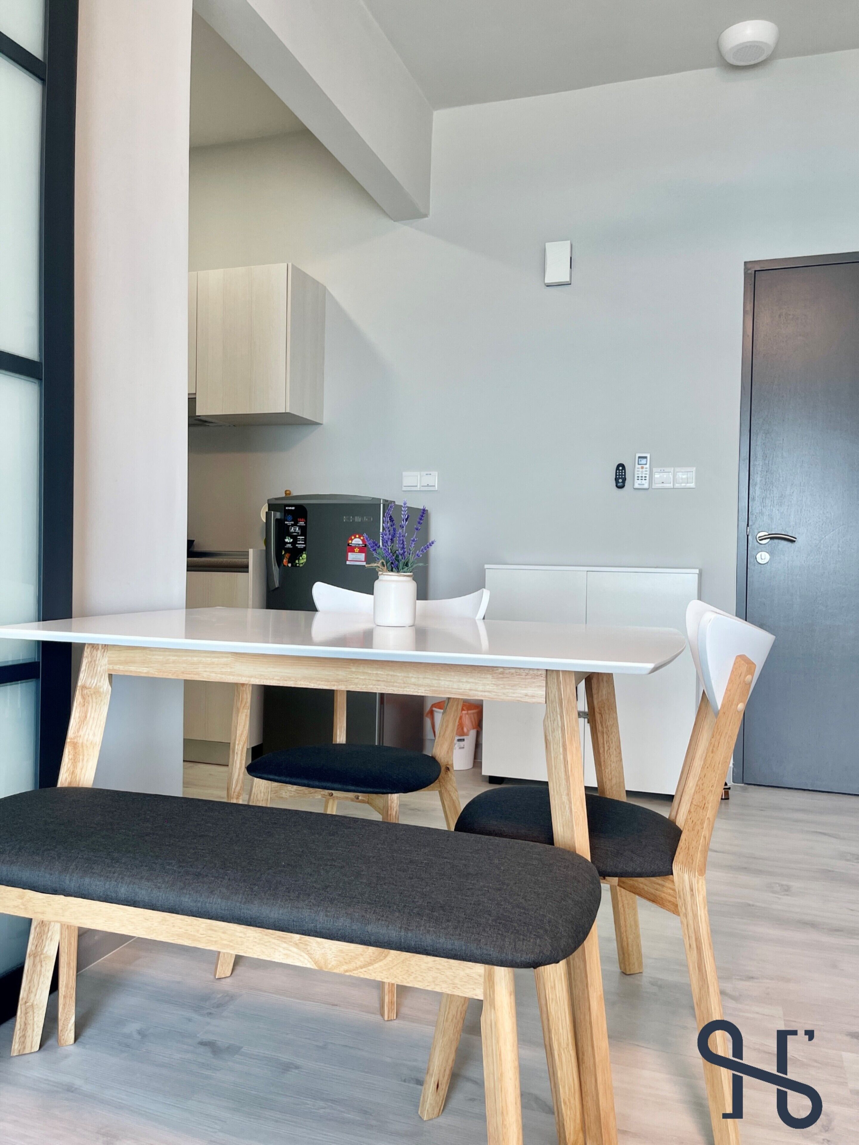 A modern kitchen with a white refrigerator, a coffee machine, and a vase with flowers on the counter.