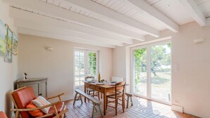A dining area with a wooden table and chairs, a bench, and a view of the outdoors through large windows. - La Paisible - 50m mer - Jardin (La Bernerie-en-Retz)