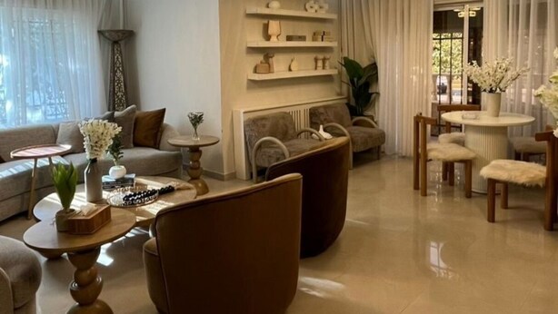 A spacious living room with a large sofa, a coffee table, and a dining area with chairs.