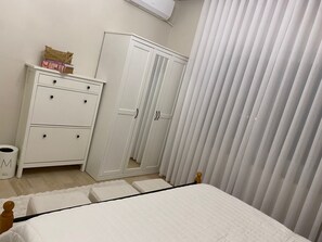A bedroom with a bed, a wardrobe, a small table with books, and a trash bin. - Sleeps 8 people! Apartment 5 minutes to Abdoun w balcony a in Dair Ghbar!  (Amman)