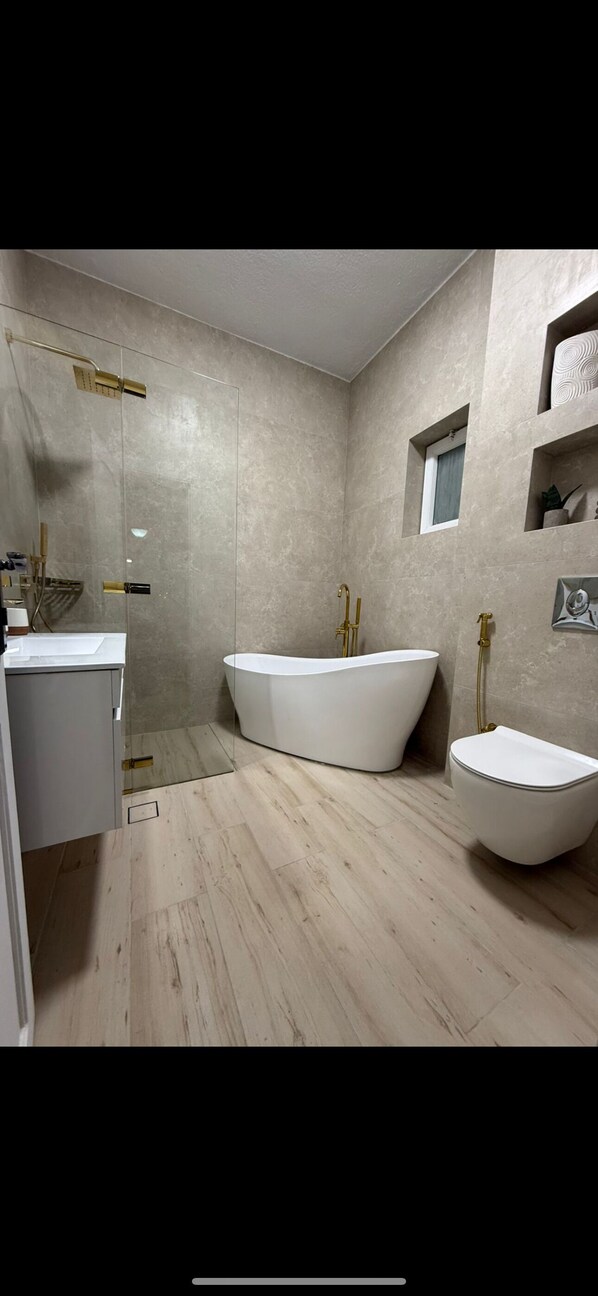 Un baño moderno con una bañera independiente, un lavabo separado y un inodoro.