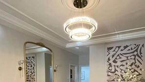 A dining area with a chandelier, a large mirror, and a modern abstract wall art piece.