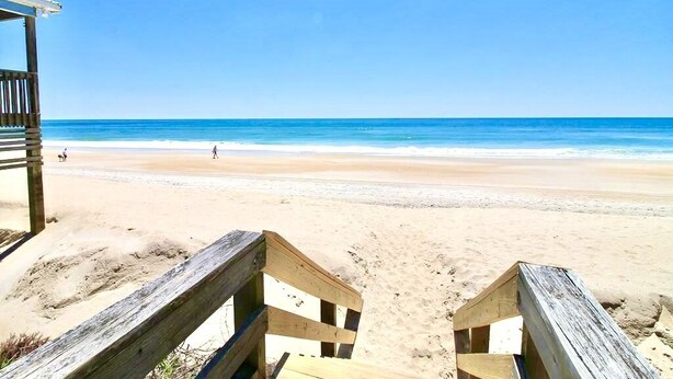 Una platja amb passeres de fusta que condueixen a la riba.