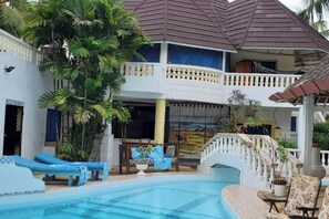 Un hotel con piscina, sillas de descanso y restaurante.