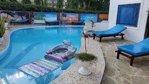 A swimming pool with lounge chairs and a floating mat. - 1 Bed Villa - Sleeps 2 - Pool - Smoking - Parking (Diani Beach kenya)