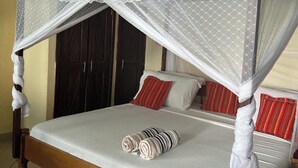 A bed with a canopy, pillows, and rolled towels. - 1 Bed Villa - Sleeps 2 - Pool - Smoking - Parking (Diani Beach kenya)