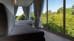 A modern room with a large window, a sofa, and a view of greenery outside. - Garden Pod @ Gardens by the Bay (Singapore)