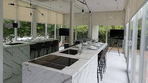 A modern kitchen with a marble countertop, built-in sink, and a large island. - Garden Pod @ Gardens by the Bay (Singapore)