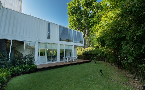 Una casa moderna de dos plantas con ventanas amplias y un patio cubierto.