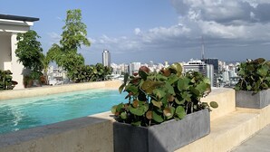 Un área de piscina en la azotea con un horizonte urbano al fondo.