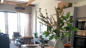 Una cocina moderna con una isla central, un comedor con mesa y sillas, y una sala de estar con sofá y una mesa de centro.