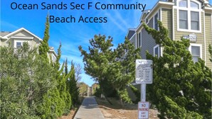 Ein hölzerner Steg führt zum Strandzugang Ocean Sands Sec F, mit Verbotsschildern für parkende Fahrzeuge.