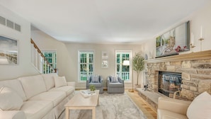 A living room with a beige sofa, two armchairs, a coffee table, a fireplace, and large windows. - Hot Tub, Family Friendly + 2 King Beds, Game Room, Secluded -Close to SB & Beach (Ellison Bay)