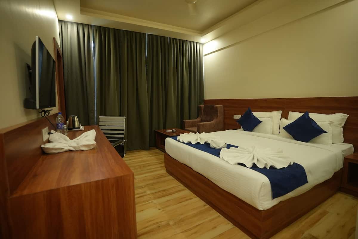 A hotel room with a wooden bed, a desk, a chair, a TV, and a curtain.