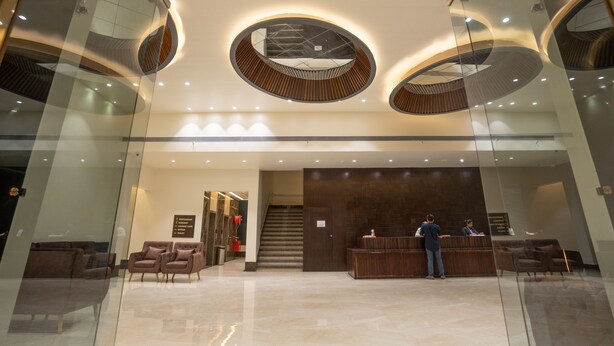 Een moderne lobby met een receptiebalie, een zithoek en een trap naar de hogere verdiepingen.