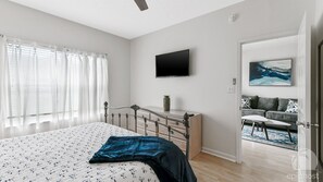 Un dormitorio con cama, cómoda, televisor de pantalla plana y un cuadro en la pared.