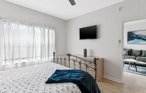 Une chambre à coucher avec un lit, une commode, un téléviseur à écran plat et un tableau accroché au mur.