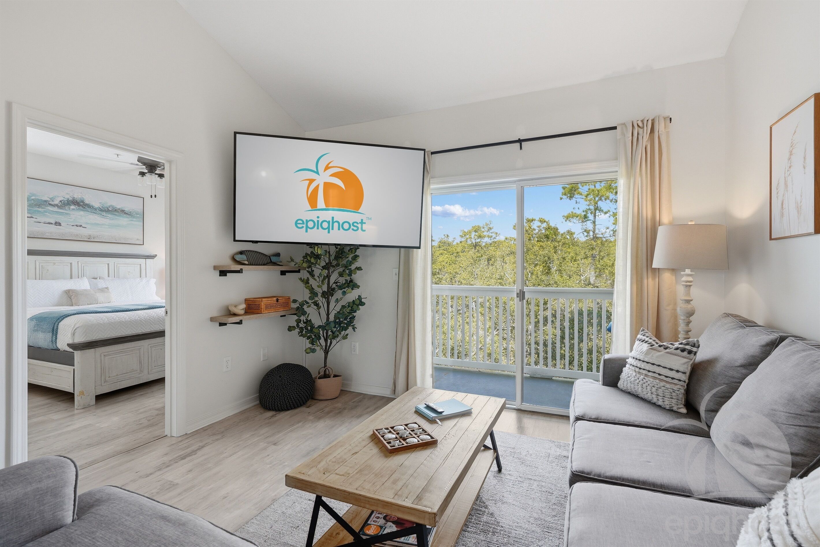 A modern living room with a flat-screen TV displaying the 'epighost' logo, a grey sofa, a wooden coffee table, and a balcony with a view of greenery.