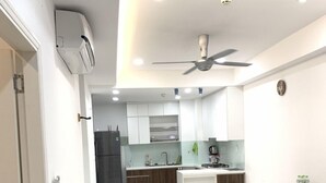 Una cocina moderna con armarios blancos, un refrigerador negro y una zona de comedor con una mesa y sillas.
