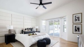 A bedroom with a bed, bedside tables, a ceiling fan, and a view through a glass door.