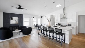 A modern kitchen with a central island, bar stools, and pendant lighting.